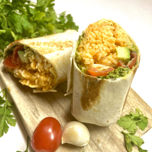 burrito with rice, avocado, pesto on cutting board