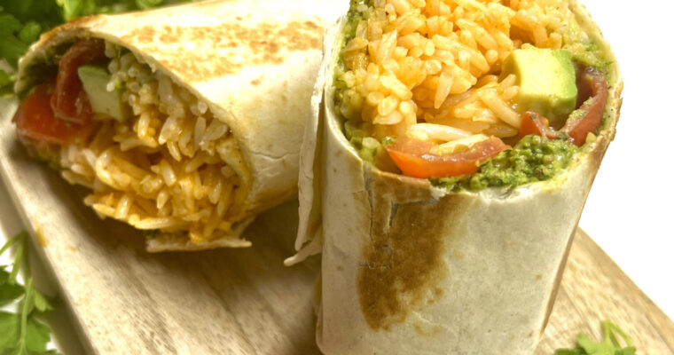 burrito with rice, avocado, pesto on cutting board