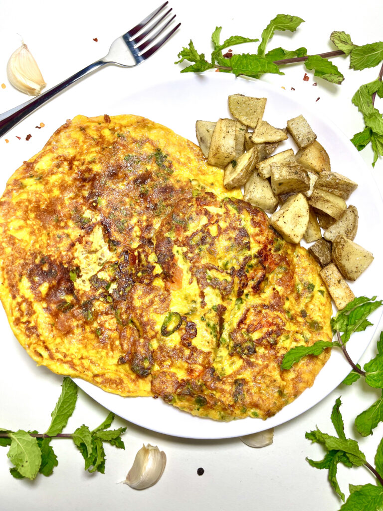 pakistani omelet on plate with potatoes