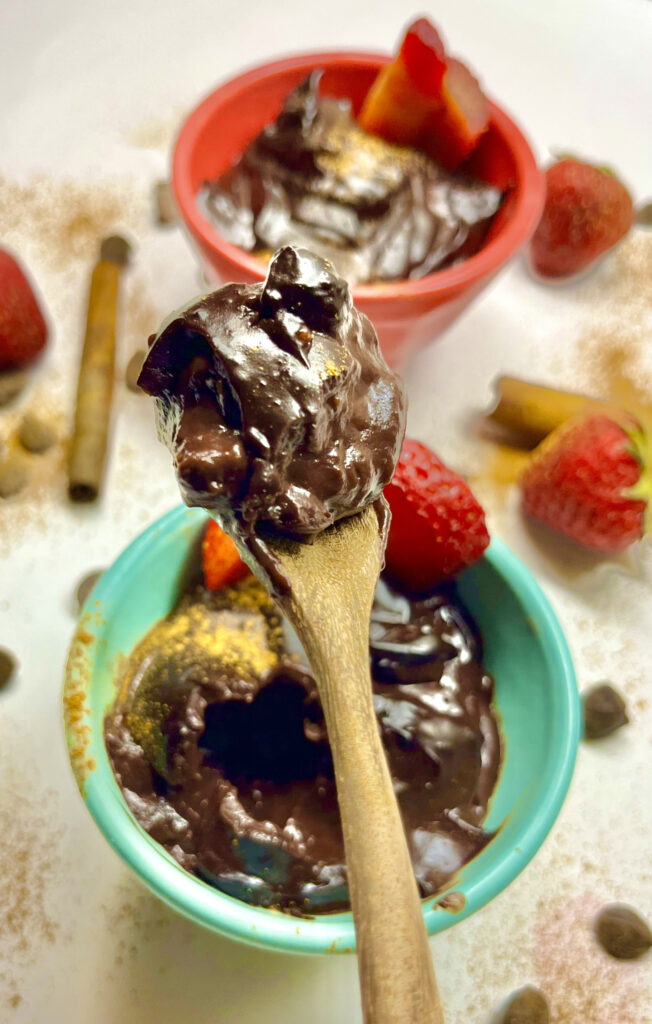 chocolate pudding in light blue bowl with wooden spoon