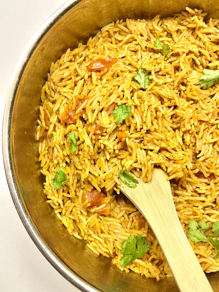 spanish rice in pan with wooden spoon