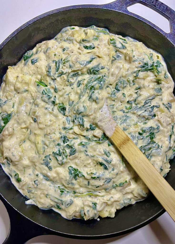 artichoke dip with stir spoon in pot