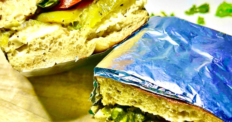 roasted veggie sandwich cut in two on serving board