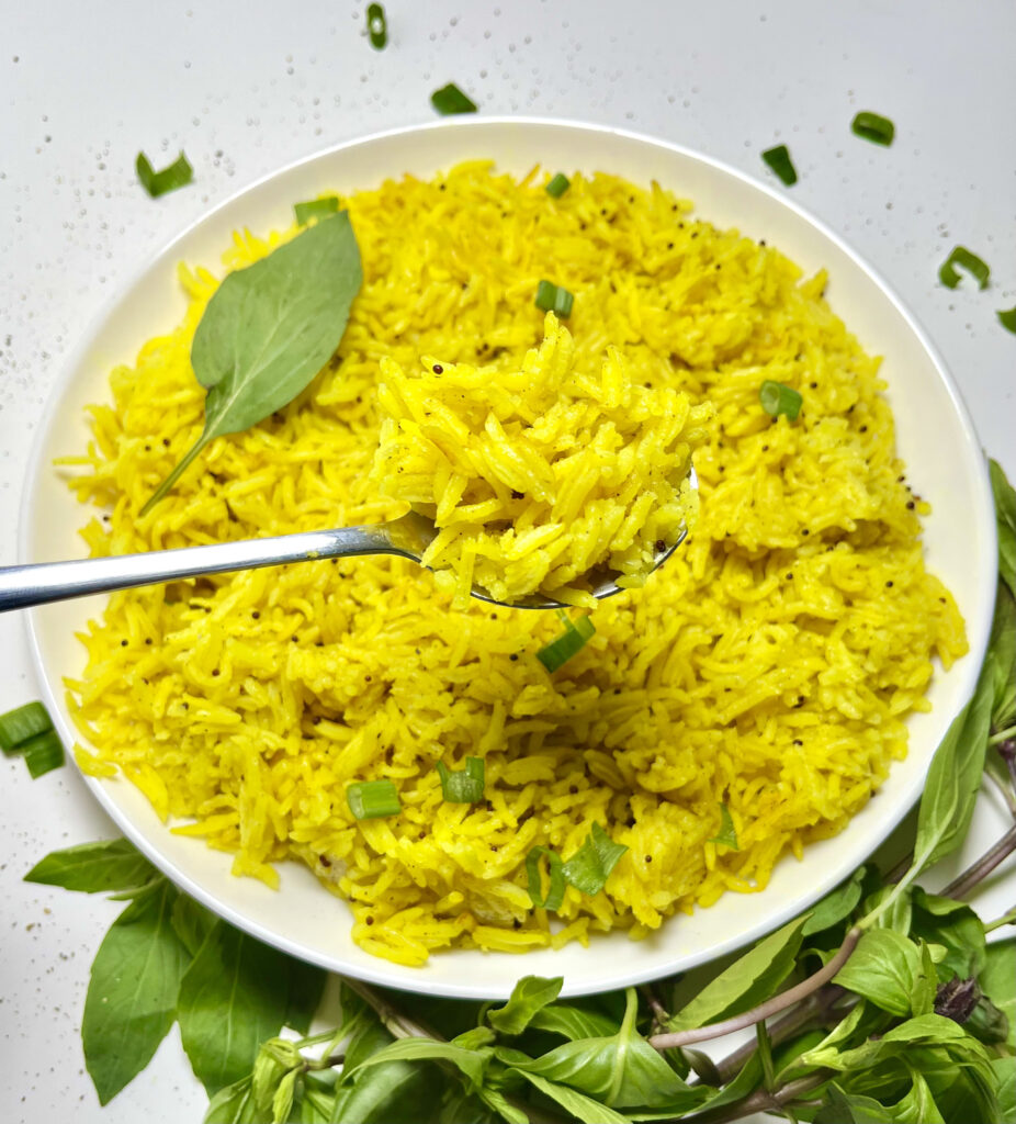 coconut turmeric rice in spoon hovering over plate