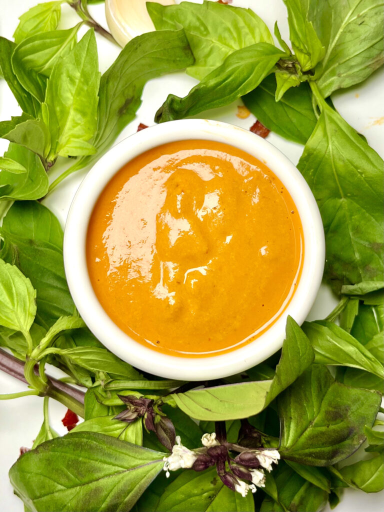 creamy chipotle dressing in cup surrounded by greens