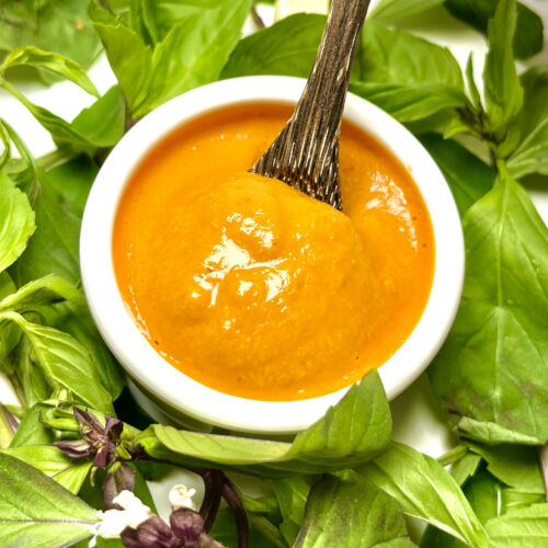 creamy chipotle dressing in cup with spoon surrounded by greens