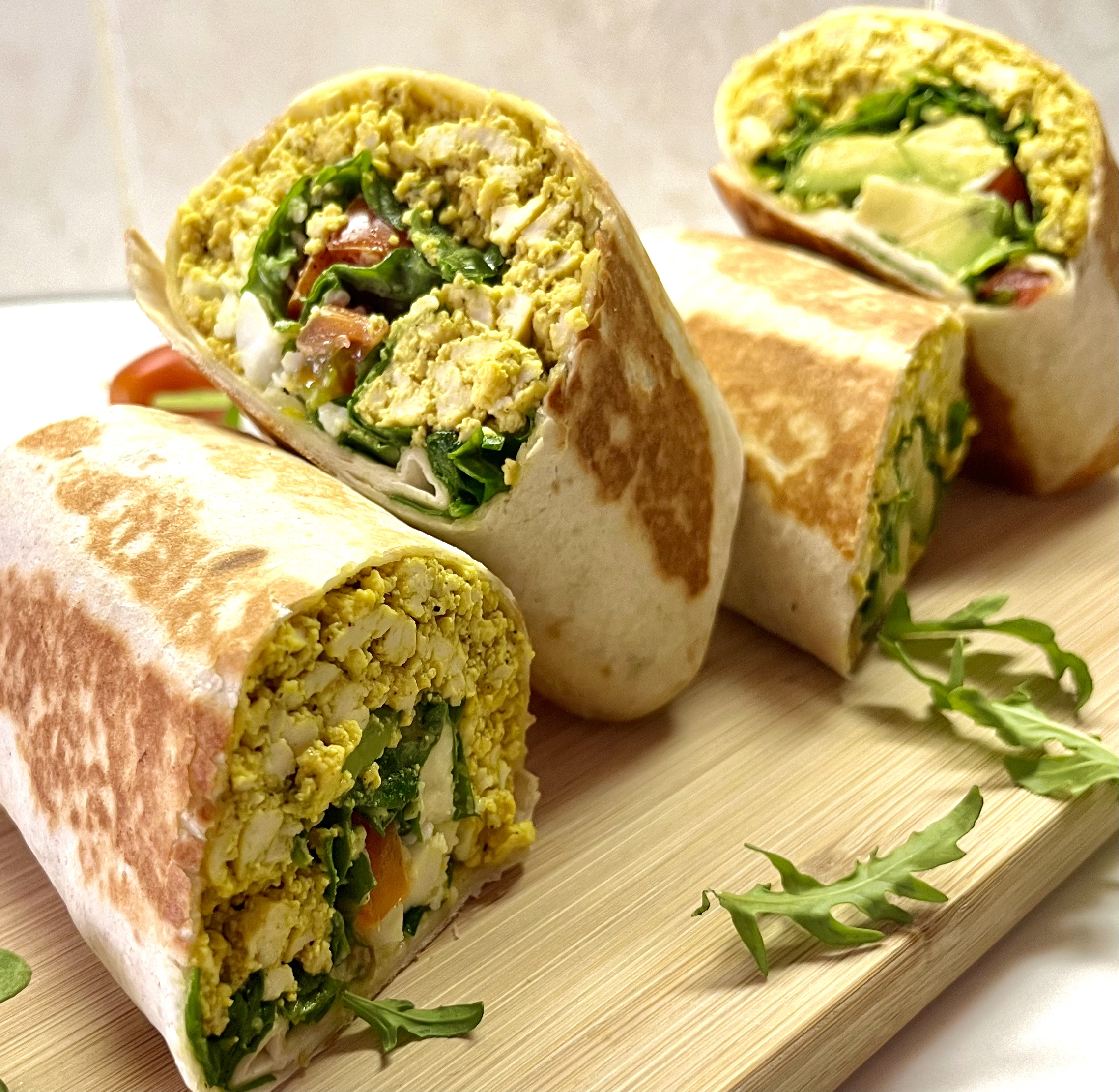 scrambled tofu breakfast burritos arranged on cutting board