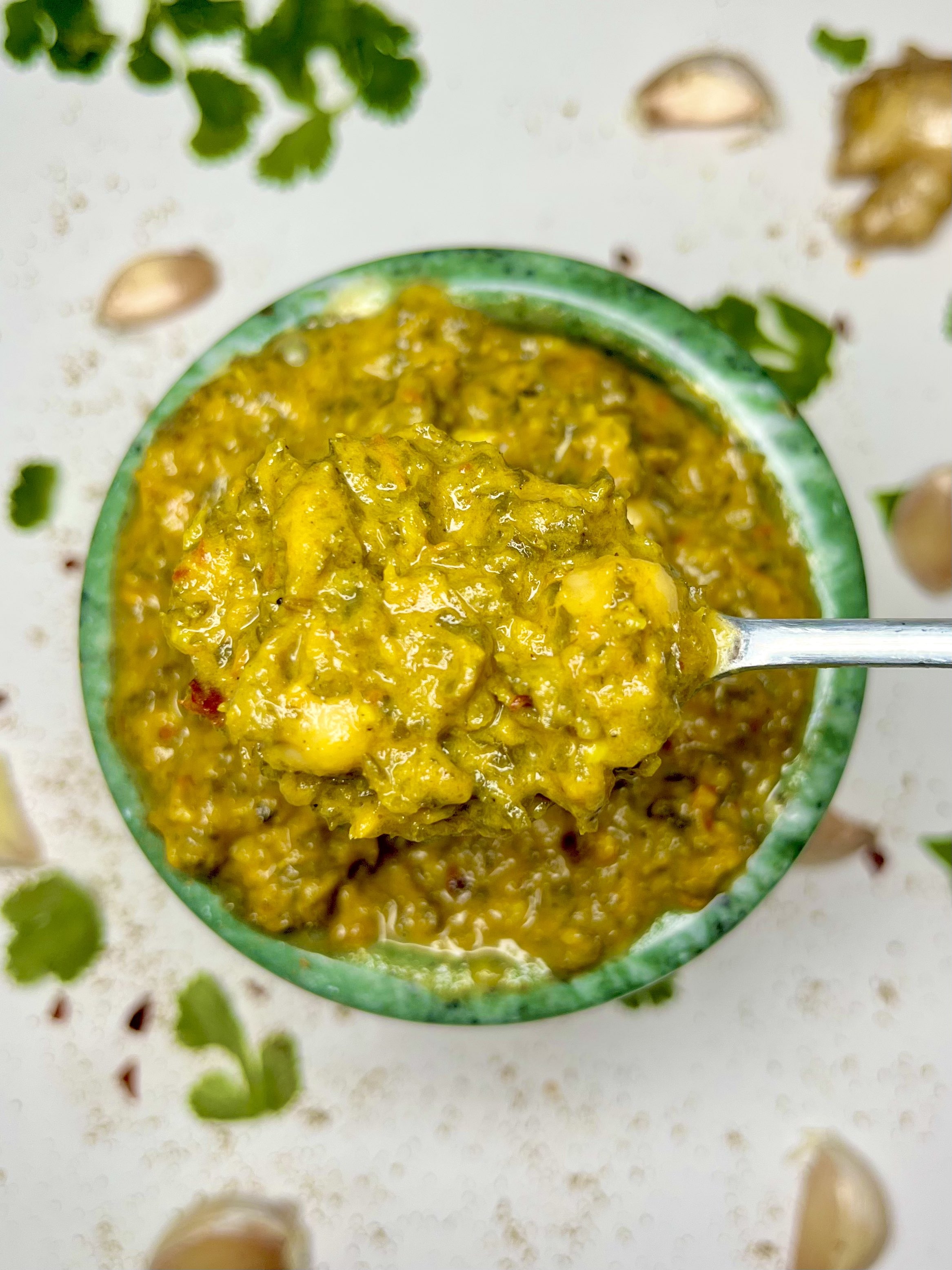 spoon holding creamy kale saag above bowl